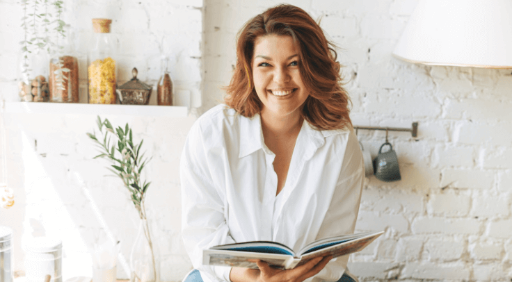 Happy woman holding a book at home
